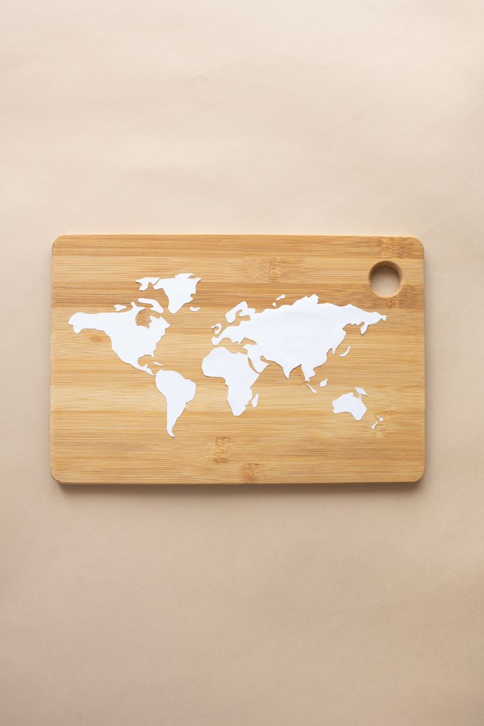 Minimalist world map cutout on a bamboo board, perfect for decor or crafts.